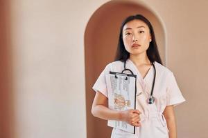 Documents in hands. Young serious asian woman standing indoors photo