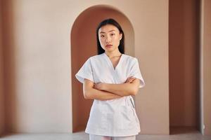 Young female doctor in white coat standing indoors photo