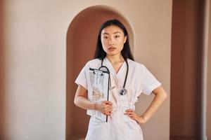 Documents in hands. Young serious asian woman standing indoors photo