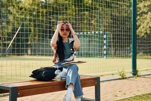 Against net of sport field. Young asian woman is outdoors at daytime photo