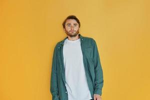 Posing for the camera, different emotions. Young man in casual clothes standing indoors in the studio photo