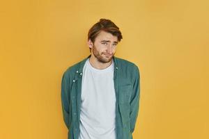 Posing for the camera, different emotions. Young man in casual clothes standing indoors in the studio photo