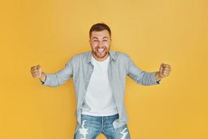 Feels good. Young man in casual clothes standing indoors in the studio photo