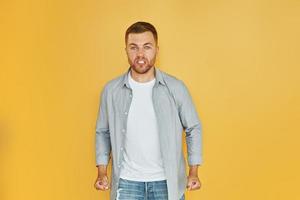 Fells anger. Young man in casual clothes standing indoors in the studio photo