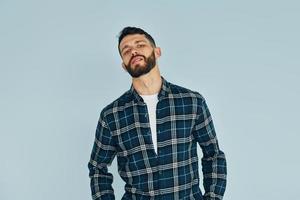 Young man in casual clothes standing indoors in the studio against blye background photo