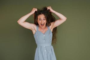 Emotional young woman in casual clothes standing indoors in the studio photo