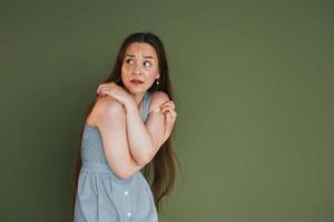 Scared young woman in casual clothes standing indoors in the studio photo