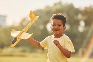 With toy in hands. African american kid have fun in the field at summer daytime photo