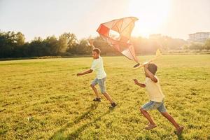 corriendo con cometa. dos niños afroamericanos se divierten juntos en el campo durante el día de verano foto