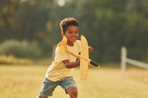 With toy in hands. African american kid have fun in the field at summer daytime photo