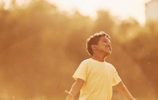 Beautiful sunshine. African american kid have fun in the field at summer daytime photo