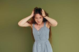 Demonstration of emotions. Young woman in casual clothes standing indoors in the studio photo