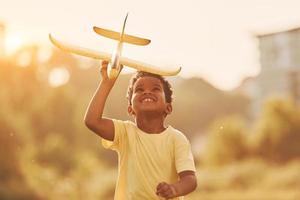 With toy in hands. African american kid have fun in the field at summer daytime photo