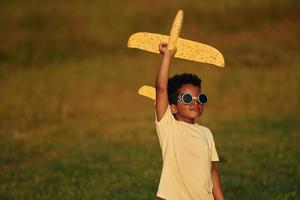 Retro style pilot sunglasses. African american kid have fun in the field at summer daytime photo