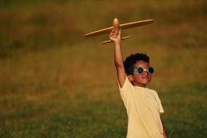 Retro style pilot sunglasses. African american kid have fun in the field at summer daytime photo