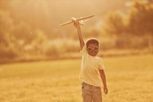 Power of imagination. Playing pilot game. African american kid have fun in the field at summer daytime photo