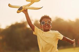 Power of imagination. Playing pilot game. African american kid have fun in the field at summer daytime photo