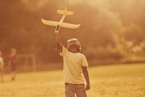 Power of imagination. Playing pilot game. African american kid have fun in the field at summer daytime photo