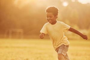 Active weekend time spending. African american kid have fun in the field at summer daytime photo