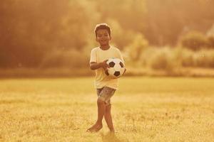 gasto de tiempo de fin de semana activo. niño afroamericano se divierte en el campo durante el día de verano foto