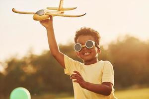 Power of imagination. Playing pilot game. African american kid have fun in the field at summer daytime photo