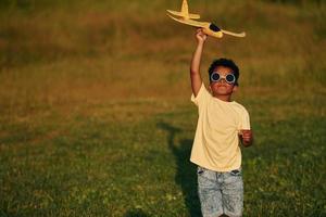 Retro style pilot sunglasses. African american kid have fun in the field at summer daytime photo