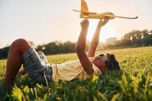 Boy with toy plane. African american kid have fun in the field at summer daytime photo