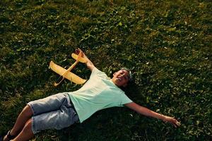 Resting on the ground. African american kid have fun in the field at summer daytime photo