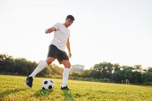 Forest on background. Young soccer player have training on the sportive field photo