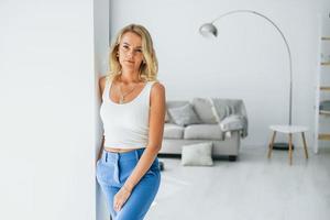 In jeans. Woman in casual clothes is indoors at home photo