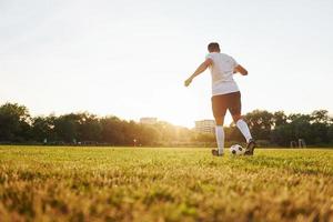 Runs with ball. Young soccer player have training on the sportive field photo