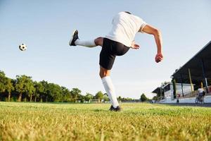 Kicks the ball. Young soccer player have training on the sportive field photo