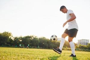 Doing different tricks. Young soccer player have training on the sportive field photo