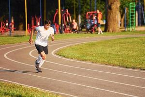 Man in sportive unifrom running on the track at daytime photo