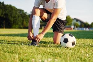 Ties laces. Young soccer player have training on the sportive field photo