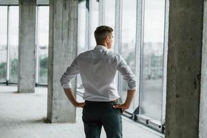 ventana grande. un joven con ropa formal está trabajando en el interior de la construcción foto