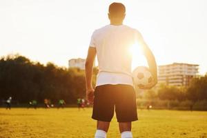 de pie y sosteniendo la pelota en la mano. el joven futbolista tiene entrenamiento en el campo deportivo foto