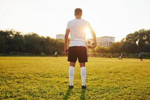 Standing and holding ball in hand. Young soccer player have training on the sportive field photo