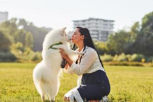 Woman is sitting on the ground of field with her cute dog photo