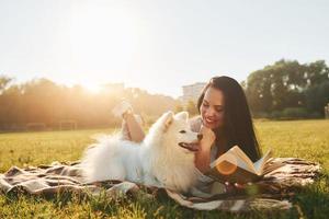 Warm weather. Woman with her dog is having fun on the field at sunny daytime photo