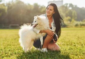 Woman is sitting on the ground of field with her cute dog photo