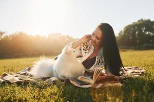 clima cálido. mujer con su perro se divierte en el campo durante el día soleado foto