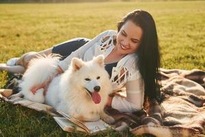 With book. Woman with her dog is having fun on the field at sunny daytime photo