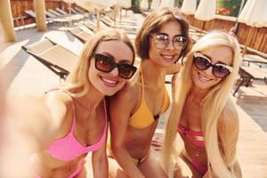 Making selfie. Women in swimsuits have fun outdoors together at summertime photo