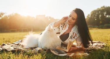 Warm weather. Woman with her dog is having fun on the field at sunny daytime photo