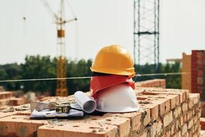 Crane is far away. Close up view of protective hard hats that laying down on the bricks photo