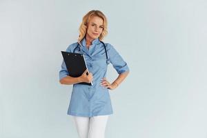 Holding documents. Young female doctor in uniform is indoors photo