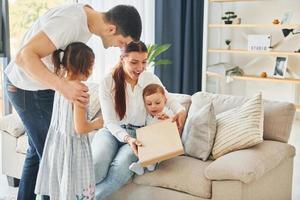 Father in casual clothes is indoors at home with his wife, daughter and son photo