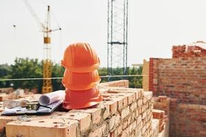 Crane is far away. Close up view of protective hard hats that laying down on the bricks photo