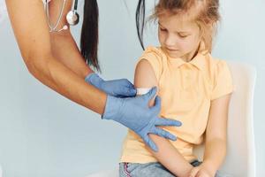 Doctor in uniform making vaccination to the little girl photo